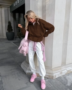 Detail of a brown fleece half-zip sweatshirt styled with a pink crossbody bag outdoors
