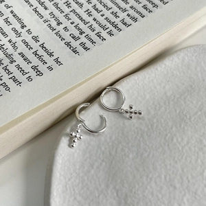 Elegant S925 sterling silver hoop earrings with small cross charms on a ceramic plate