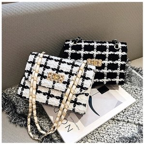Detailed view of tweed plaid shoulder bags with metal chain straps on a textured sofa
