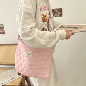 Détail du sac cabas matelassé rose montrant les motifs ronds et l'étiquette en tissu