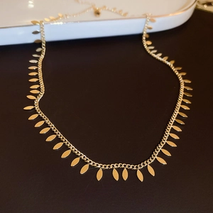 Close-up of golden leaf pendant choker necklace on a white ceramic plate