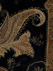 Macro shot of detailed gold embroidery and beadwork on premium black velvet fabric