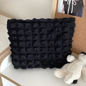 Close-up of black bubble textured fabric storage bag with pleated ruffle details