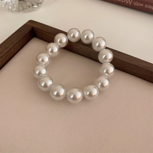 Detailed view of large glossy cream pearls on a flexible French style stretch bracelet