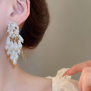 Detailed close-up of elegant chandelier tassel earrings with pearls and crystals on a model