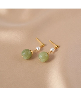 Detail of vintage drop earrings with freshwater pearls and green jade on silk fabric