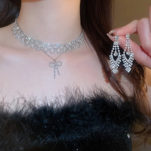 Detailed view of silver bow necklace and earrings set with sparkling rhinestones