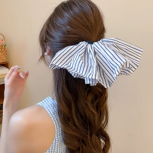 Blau-weiß gestreifte Schleifen-Haarspange an gewelltem Haar für einen stilvollen Look