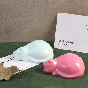 Detail of pink and blue cat-shaped resin figurines sleeping on a desk as home decor