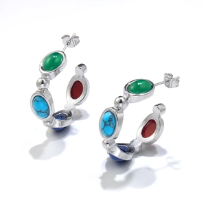 Detailed view of silver C-shaped earrings inlaid with colorful oval zircon gemstones