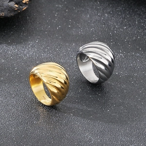 Détail macro de bagues bombées or et argent avec nervures spirales et finition métallique