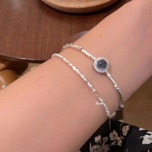 Detail of silver bamboo-style chain and faceted natural aquamarine stone on wrist