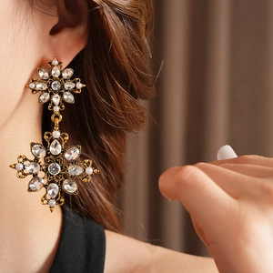 Détail des boucles d'oreilles vintage dorées avec cristaux brillants et perles blanches