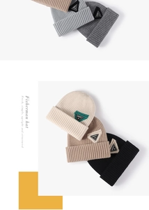 Detailed close-up of thick ribbed knit texture and embroidered triangle patch on beanies