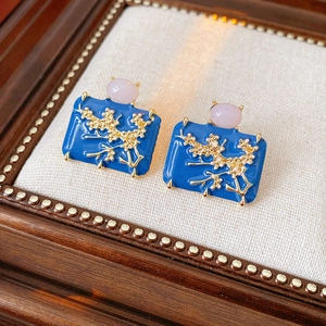 Macro shot of vintage blue enamel earrings with pink gems and gold leaf details