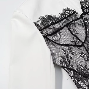Detail of elegant black lace patchwork on a white dress fabric with fine mesh patterns