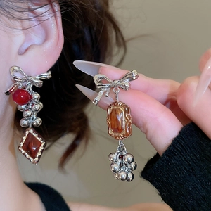 Detail view of asymmetric bow earrings with ruby and amber stones on model