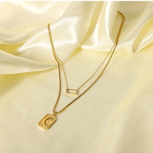 Detail of gold layered stainless steel necklace with sun and moon pendant on yellow silk