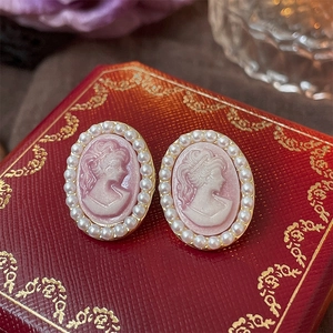 Macro shot of vintage cameo earrings with pink lady relief and pearl border detailing