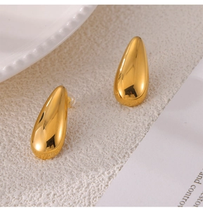 Macro shot of minimalist gold teardrop earrings with a glossy polished metal finish
