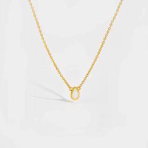 Macro shot of gold teardrop pendant necklace featuring a white opal-like gemstone