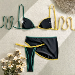 Detailed flat lay of a three-piece black bikini set with neon trim and metal ring accents