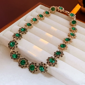 Detailed close-up of emerald green flower clusters on vintage gold link bracelet