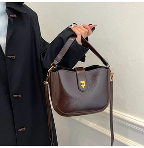 Detail of dark brown polished oil wax leather bucket bag with golden metal buckle clasp