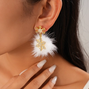 Close-up of golden snowflake earrings with white fluffy pompons and sparkling rhinestones