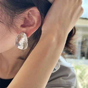 Minimalist silver liquid metal earrings with irregular texture shown on a model
