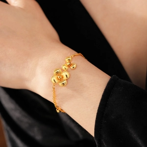 Macro detail of gold plated flower bracelet featuring matte petals on a black velvet background