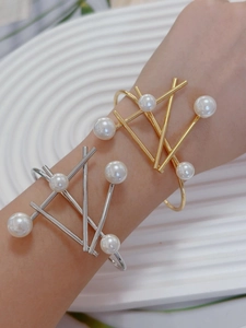 Close-up of irregular geometric gold and silver bracelets with elegant pearl accents