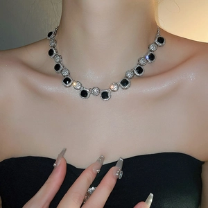 Close-up of geometric square necklace with black and clear rhinestones on model