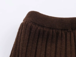 Close-up of dark brown ribbed knit fabric showing texture and waistline detailing