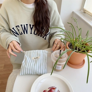 Detail of mint green striped drawstring pouch on a cafe table with lifestyle elements