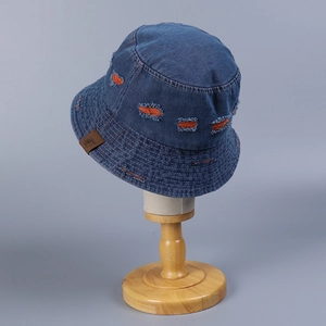 Detail of distressed denim bucket hat featuring orange contrast stitching and leather patch