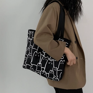 Detailed shot of large capacity black canvas tote bag with cat print on a fashion model