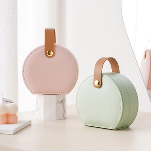 Portable round jewelry box in pink and green PU leather with a golden metal snap closure
