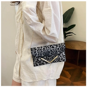 Close-up of leopard print envelope clutch with gold V-metal trim and chain strap