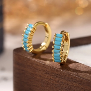 Macro detail of 925 silver gold-plated huggie earrings set with square turquoise stones