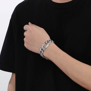 Détail d'un bracelet à maillons cubains argenté étincelant porté au poignet sur fond blanc