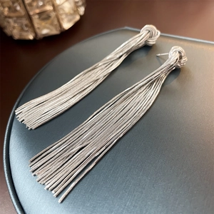 Close-up of silver knot tassel earrings featuring polished long metal chain fringe details