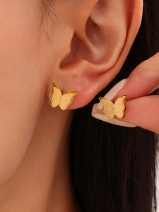 Close-up of matte gold butterfly earrings showing the frosted texture and refined details