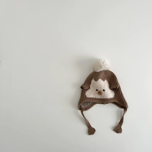 Detail of baby knit hat with faux fur pompom and cute animal pattern for winter warmth