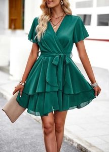 Détail de robe verte à col en V avec ourlet à volants superposés et ceinture assortie nouée