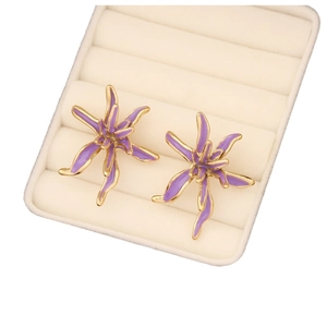 Elegant purple flower stud earrings with gold trim on a cream jewelry storage box display