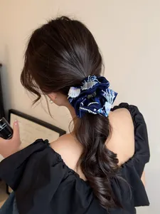 Detail of navy blue velvet hair scrunchie with silver floral embroidery and pearls
