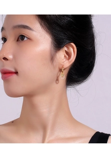 Close-up of elegant gold heart earrings with zircon inlay worn by a female model