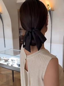 Elegant back view of model wearing a large black satin bow hair clip in a low bun style