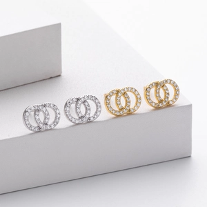 Close-up of interlocking double ring earrings with white cubic zirconia in gold and silver